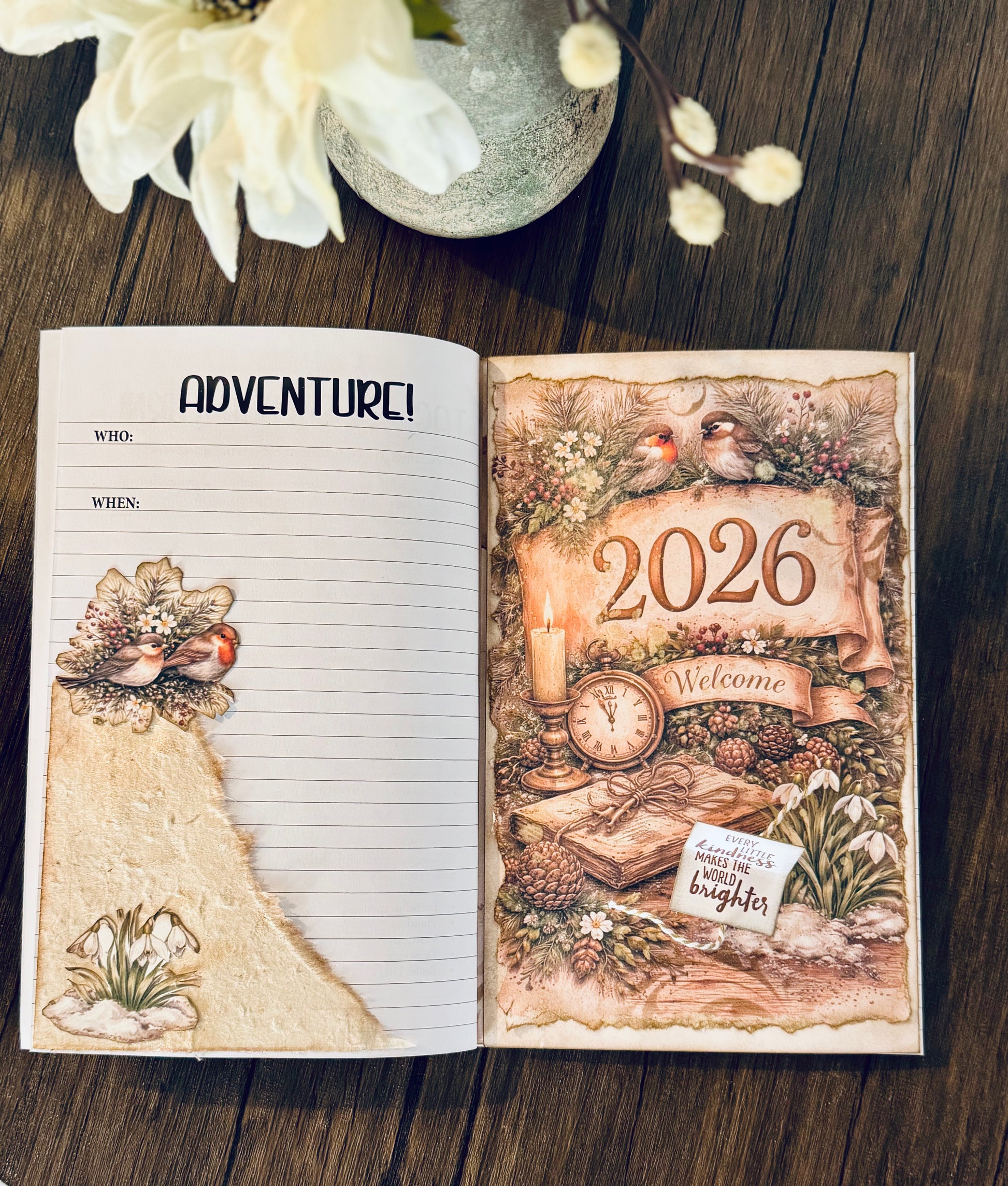 Open book with decorative pages featuring 'Adventure!' and '2026' on a wooden surface.
