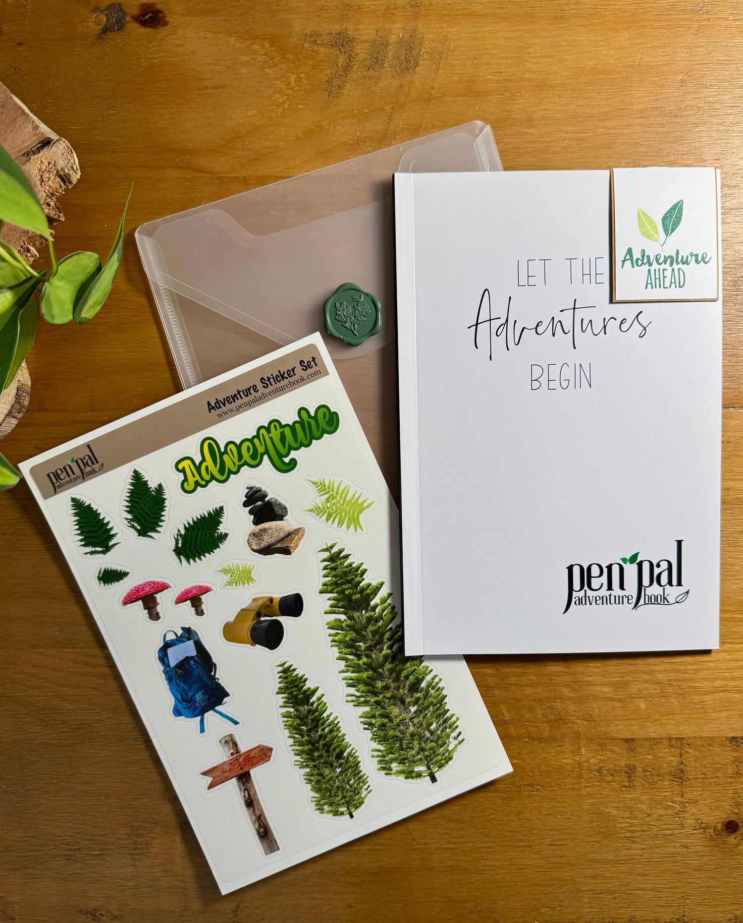 Pen & Pal Adventure Sticker Pack and notebook on a wooden surface